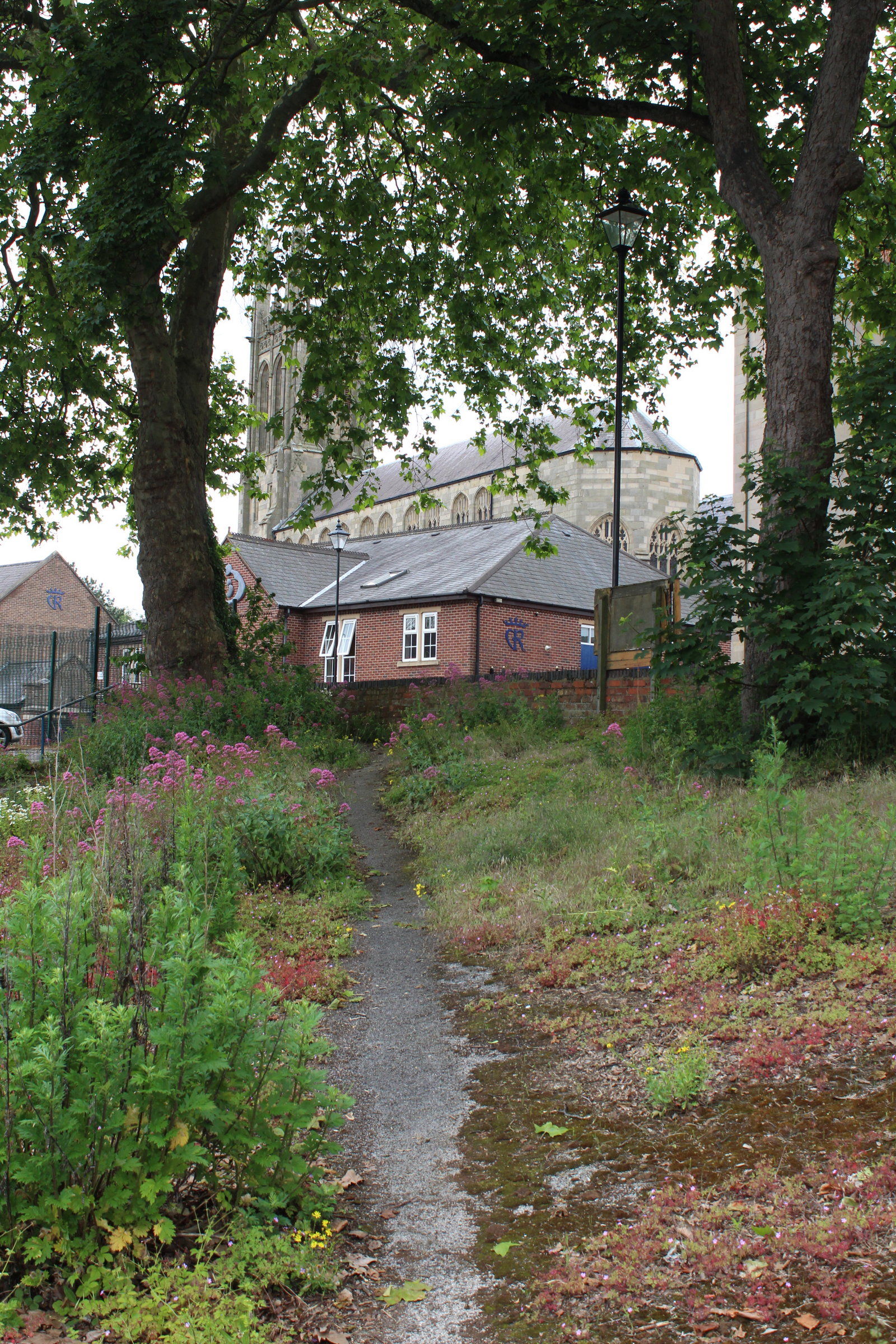 Path leading down into Saint Alkmund's Town Green from Darley Lane. St Mary's Church in the background.